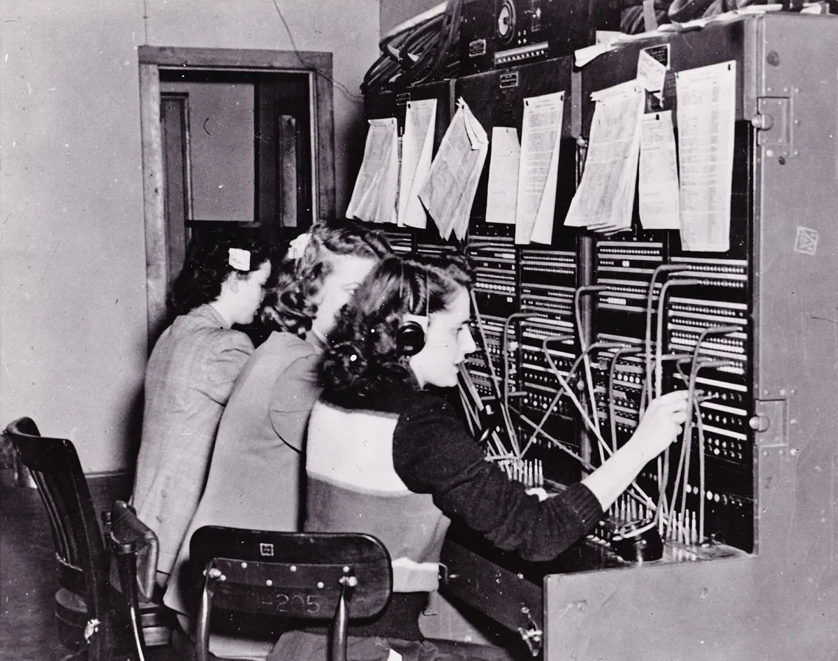 Three telephone operators connecting calls at a switchboard in 1950