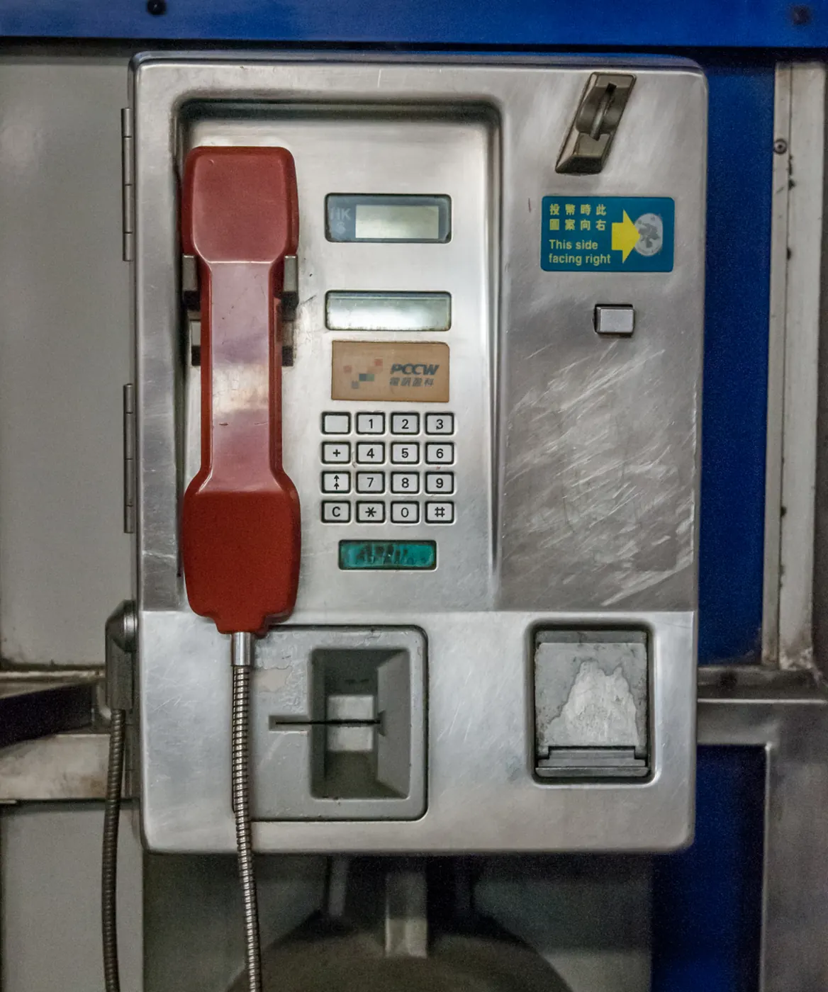 Close-up of a coin-operated public phone with a red handset in Hong Kong